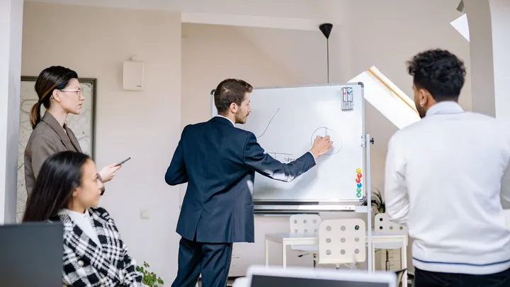 Équipe debout devant un tableau blanc lors d’une réunion de travail
