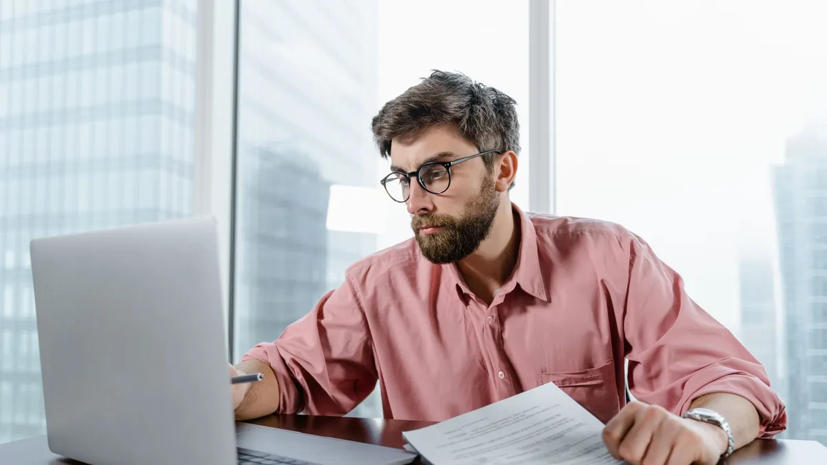 Homme d’affaires consultant des documents devant un ordinateur portable