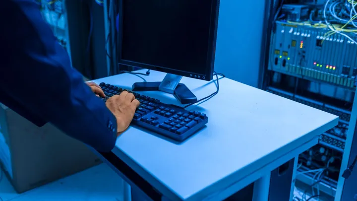 Technicien configurant un équipement réseau près d’une baie de serveurs
