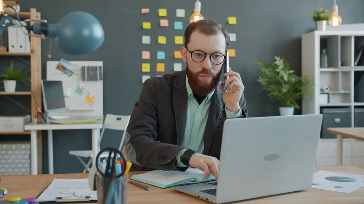 Homme au téléphone travaillant sur un ordinateur portable dans un bureau