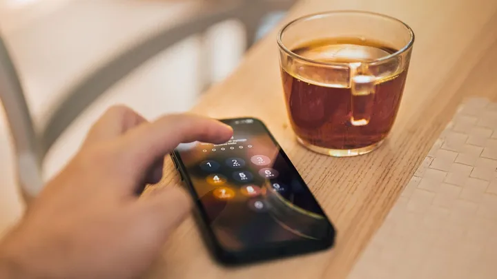 Main déverrouillant un smartphone par code sur une table