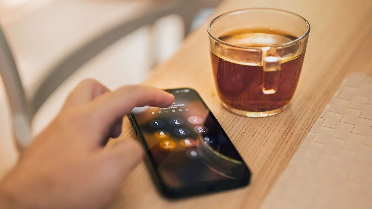 Main déverrouillant un smartphone par code sur une table