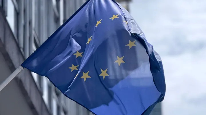 Drapeau de l’Union européenne devant un bâtiment institutionnel moderne
