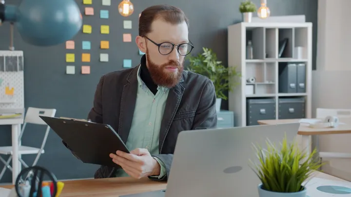Personne comparant une liste de contrôle imprimée avec l’écran de son ordinateur portable