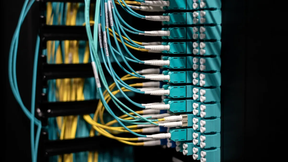 Câbles réseau de couleurs différentes raccordés à un panneau de brassage, organisés par groupes